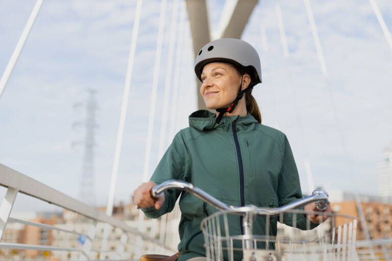Pyöräilevä nainen hymyilee kevyenliikenteen sillalla.